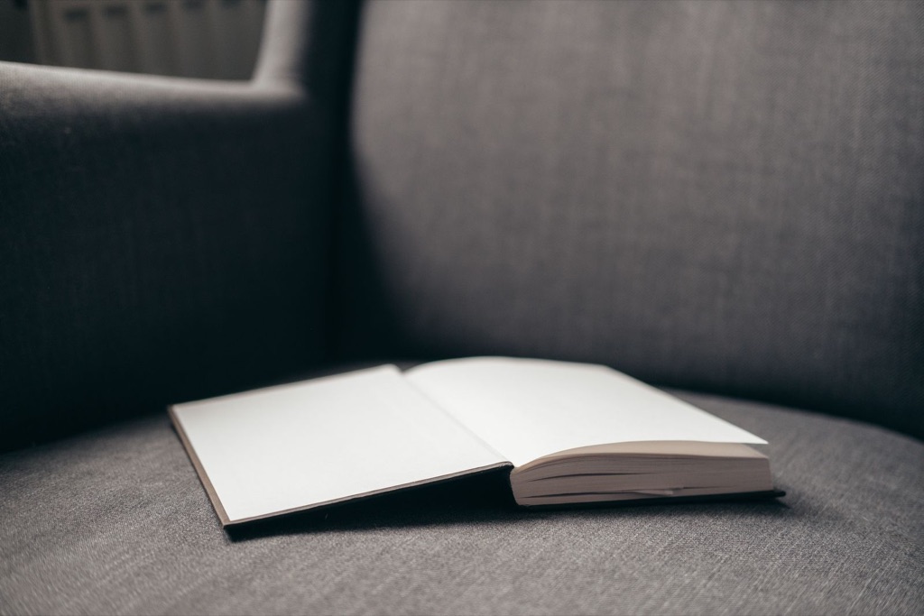 An open book left on an empty gray armchair