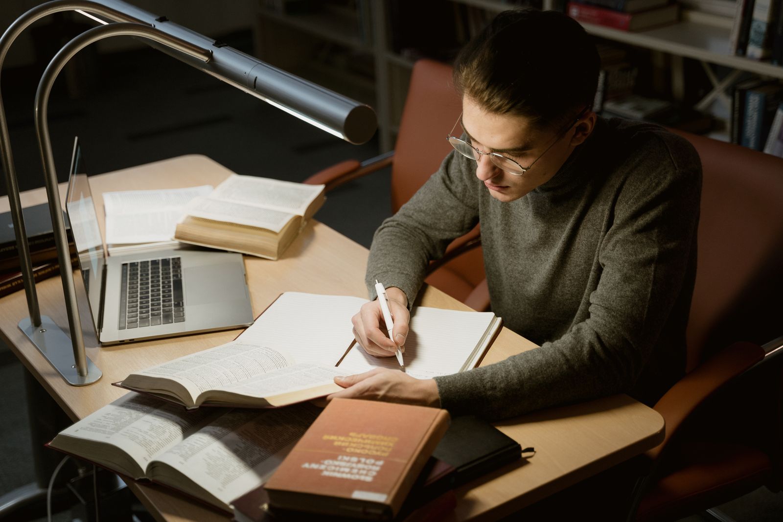 A person reading a book and taking notes with a pen