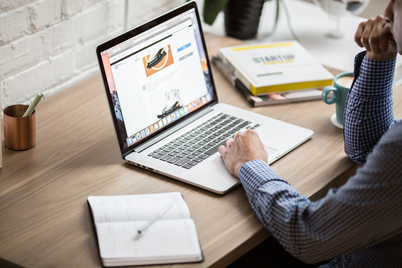 A laptop, an open book, and a cup of coffee on a wooden desk